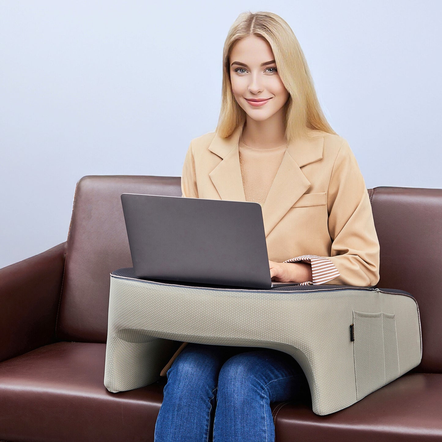 Woman working on a laptop using a lap desk pillow on a couch