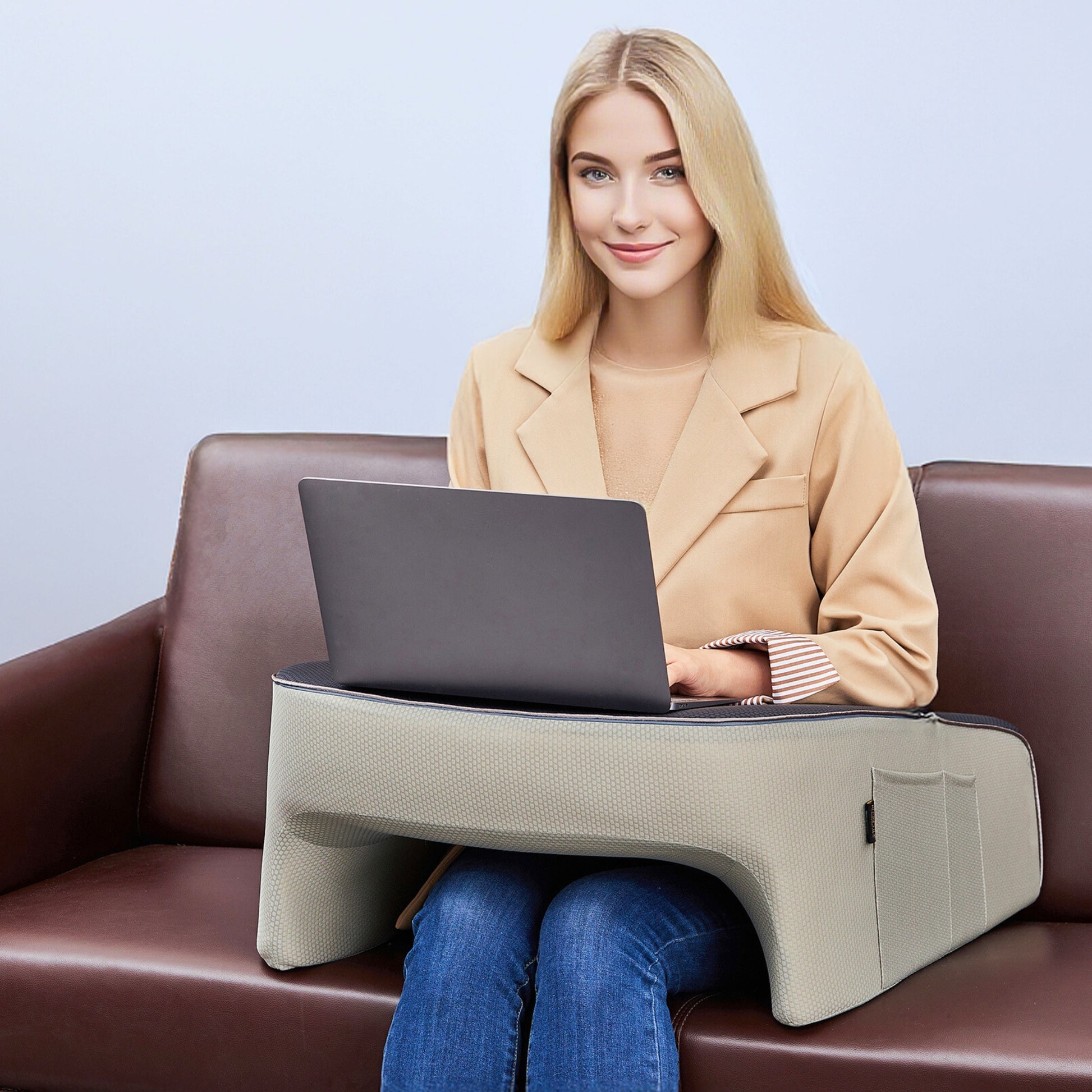 Woman working on a laptop using a lap desk pillow on a couch