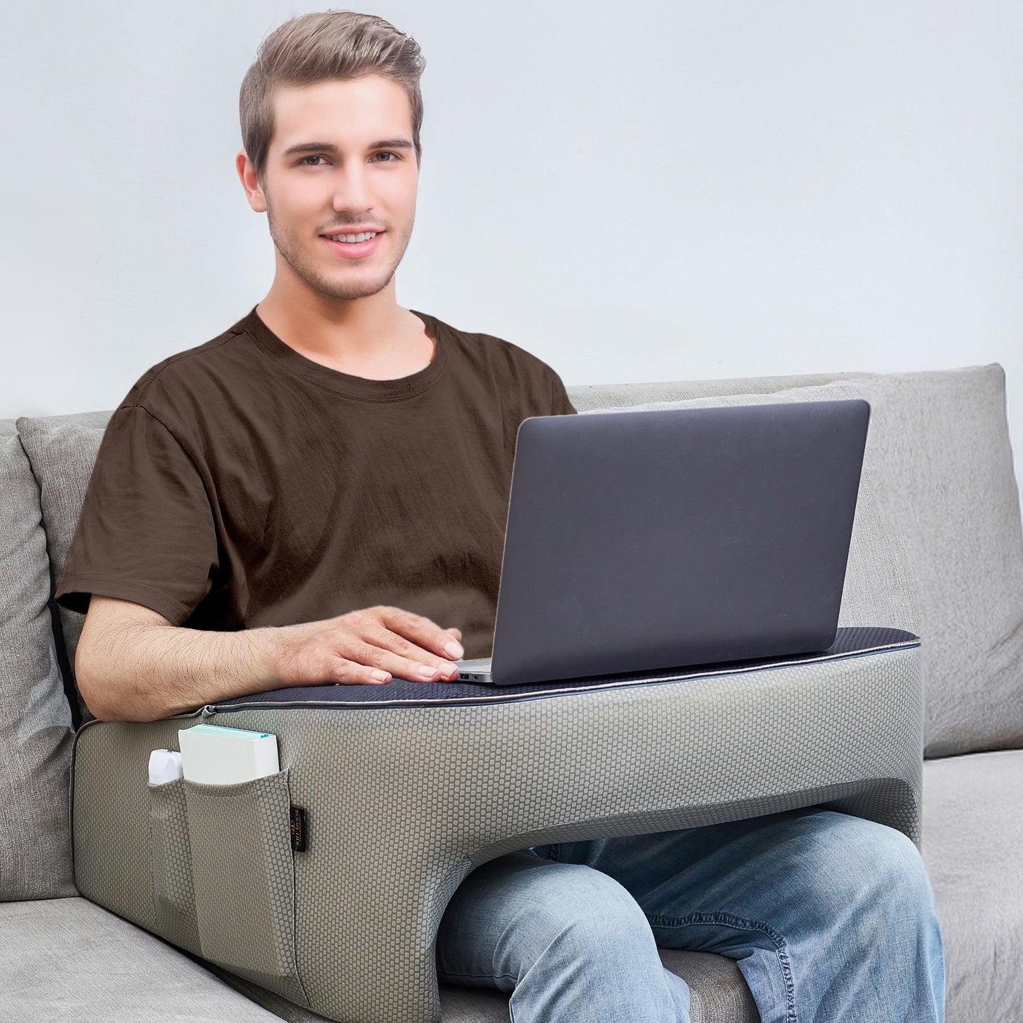 Man using a memory foam lap desk pillow on a couch with a laptop