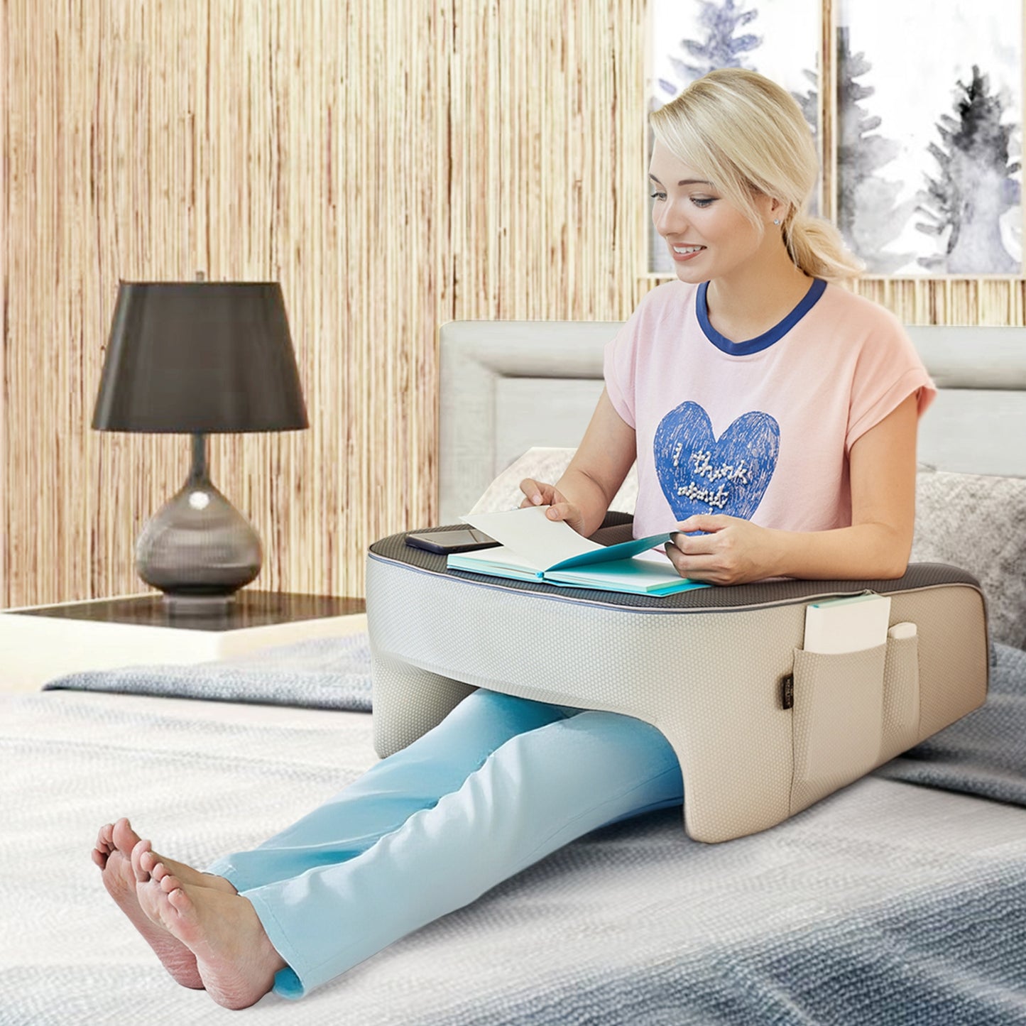 Woman reading in bed using a lap desk pillow for comfort and support